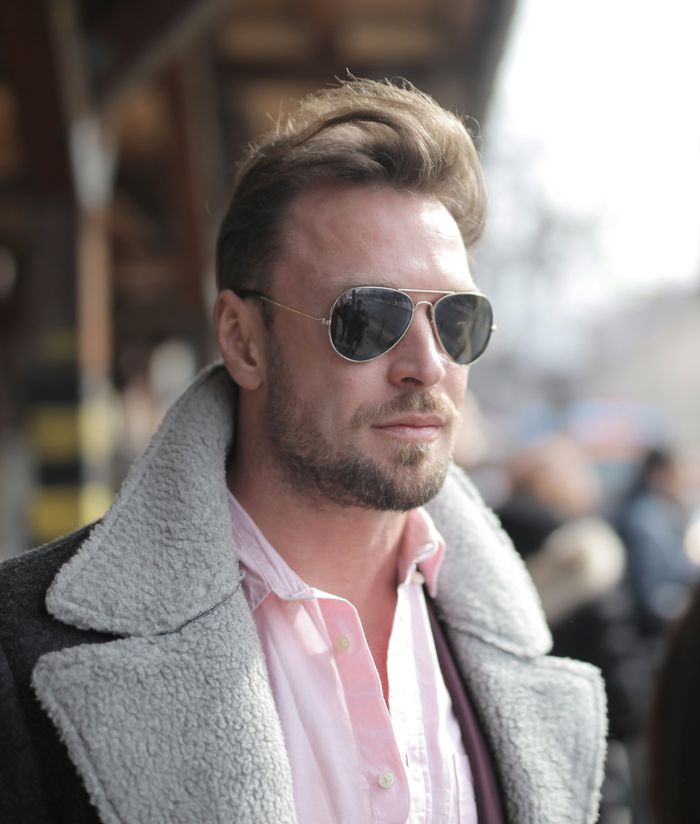heros-img Fashionable man wearing sunglasses and shearling jacket. Urban outdoor setting.